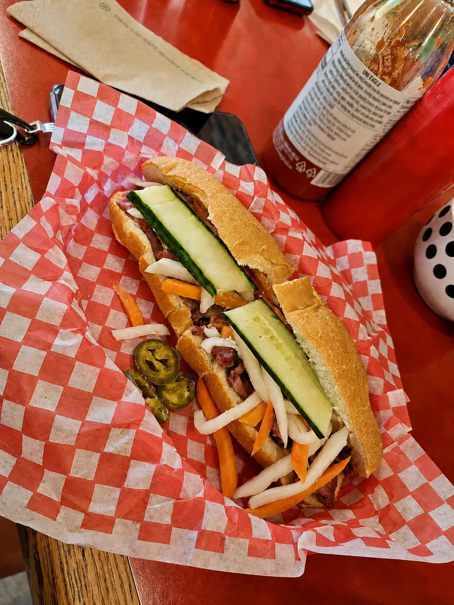 Vietnamese baguette with vegetables on red and white deli paper