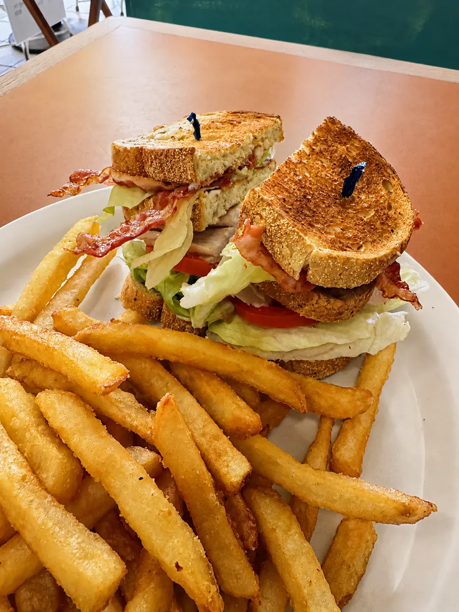 Clubhouse sandwich and fries on a café table at Broughton Street Deli
